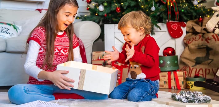 Children open Christmas gifts under the tree. Selective focus. Kid.