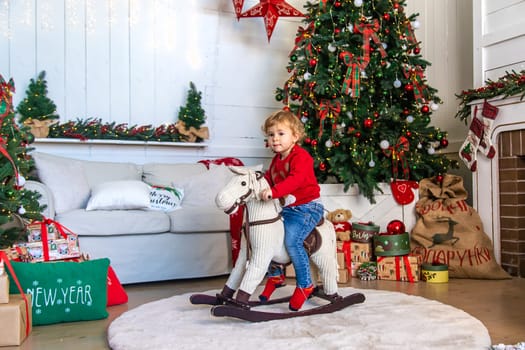 Child on horseback near the Christmas tree. Selective focus. Kid.