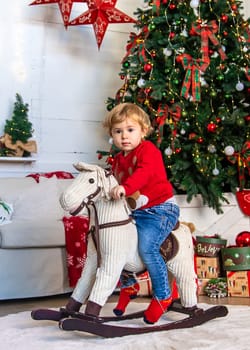Child on horseback near the Christmas tree. Selective focus. Kid.