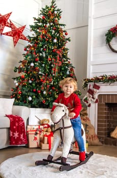 Child on horseback near the Christmas tree. Selective focus. Kid.