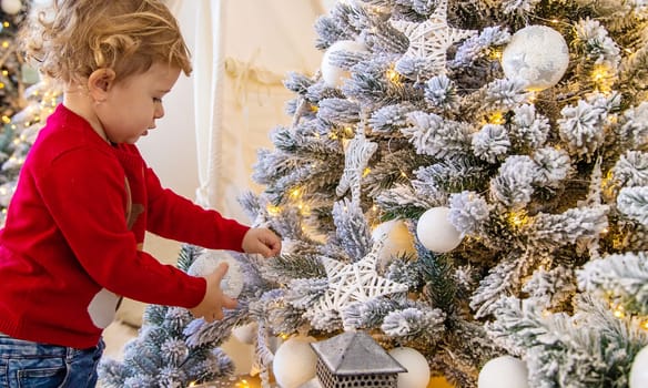 The child hangs a decoration on the Christmas tree. Selective focus. Kid.