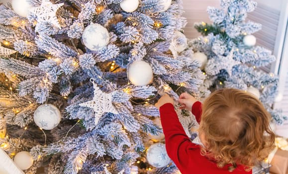 The child hangs a decoration on the Christmas tree. Selective focus. Kid.