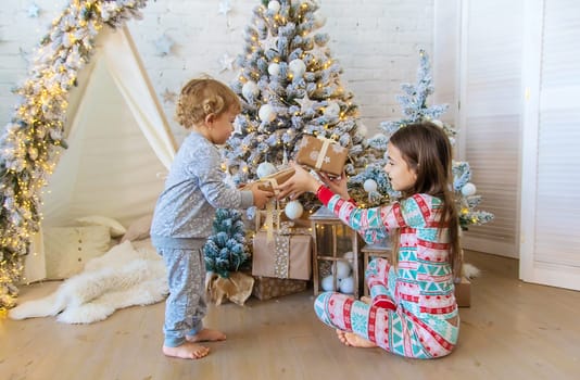 Child open Christmas gifts under the tree. Selective focus. Kid.