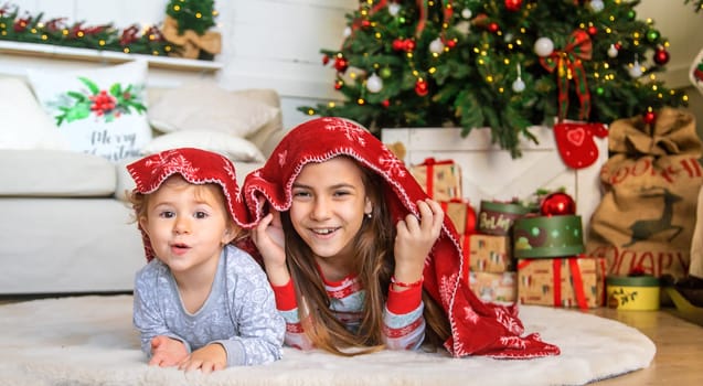 Children near the Christmas tree play with a blanket. Selective focus. Kid.