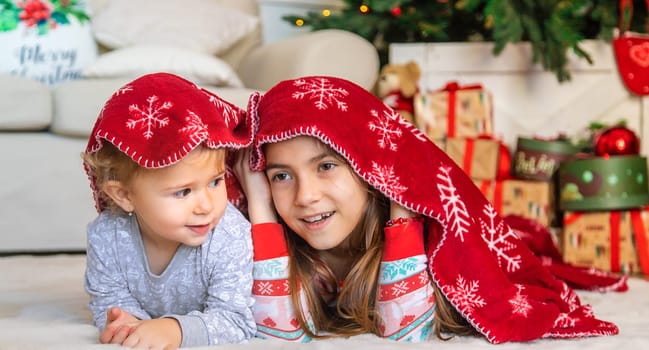 Children near the Christmas tree play with a blanket. Selective focus. Kid.