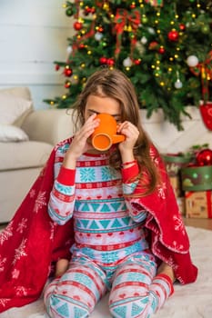 Children drink tea near the Christmas tree. Selective focus. Kid.