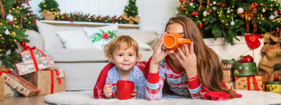 Children drink tea near the Christmas tree. Selective focus. Kid.