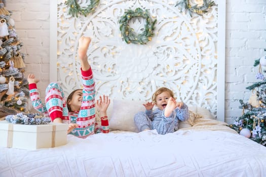 Children jump on the bed near the Christmas tree. Selective focus. kid.