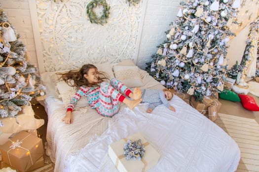 Children jump on the bed near the Christmas tree. Selective focus. kid.