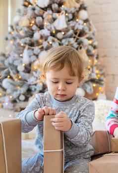 Child open Christmas gifts under the tree. Selective focus. Kid.