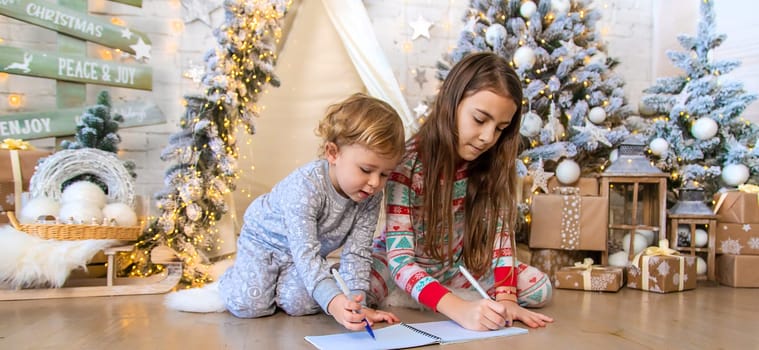 Children write a letter to Santa under the tree. Selective focus. Kid.