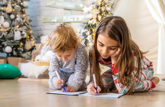 Children write a letter to Santa under the tree. Selective focus. Kid.