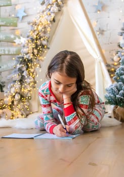 Children write a letter to Santa under the tree. Selective focus. Kid.