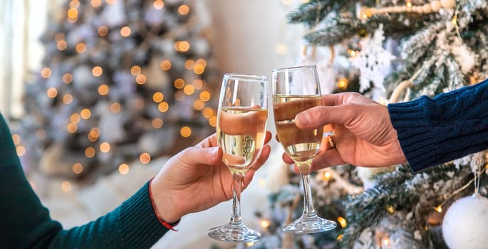 Man and woman with champagne in their hands near the Christmas tree. Selective focus. Couple.