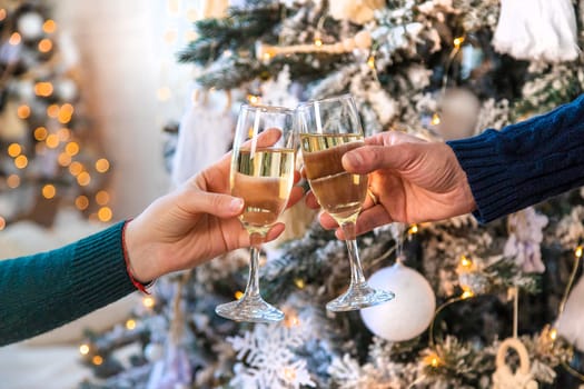 Man and woman with champagne in their hands near the Christmas tree. Selective focus. Couple.