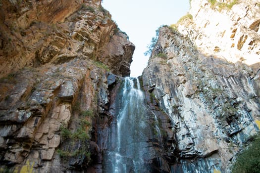 waterfall among rocks in a mountain stream. Water landscape surrounded by huge rocks in a summer forest