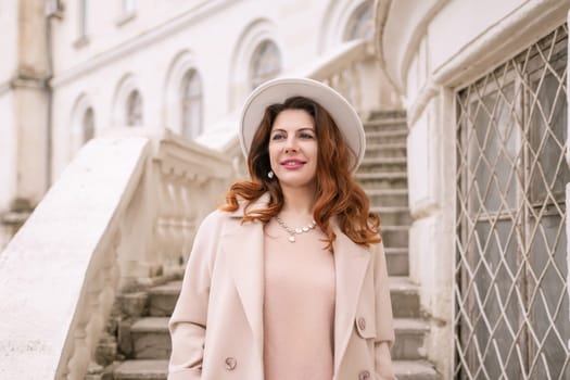 woman in elegant coat and hat against an intricate architectural backdrop, harmoniously blending modern fashion with historical allure. The soft daylight adds to its timeless appeal