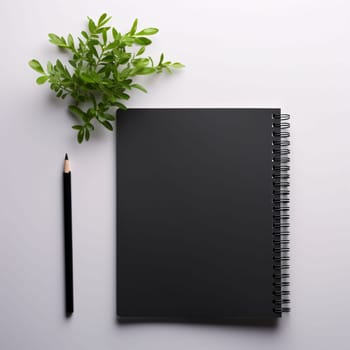 Notebook black blank pages, pencil on the left, green branch with leaves, light background, space for your own content. Graphic with space for your own content.