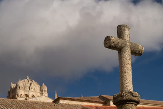 A stone cross in the foreground at San Claudio de Olivares square with the dome of the Romanesque Zamora Cathedral subtly blurred in the background.