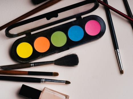 Brushes and palette with eye shadow close-up on pink background