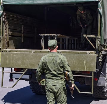 Soldiers unload firearms from a military truck. A soldier in the back of a truck.