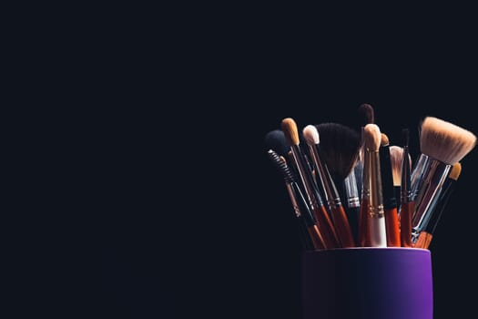 set of professional makeup brushes close up with copy space on dark background