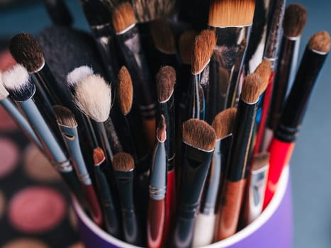 set of makeup brushes on the background of a professional palette with eye shadows close-up. The concept of women's cosmetics for beauty