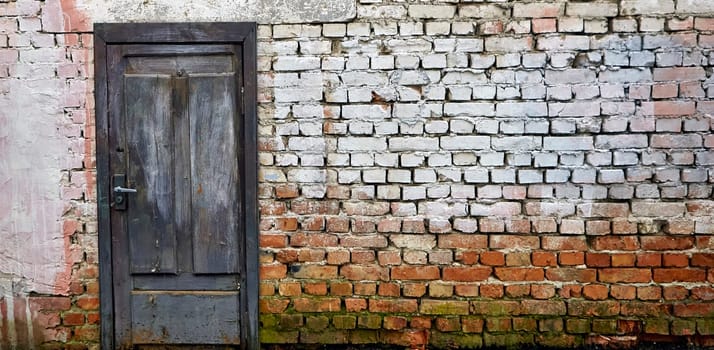 The vibrant blue wooden door, set against the weathered brick wall and adorned with remnants of whitewash, exudes a sense of history and charm, creating a timeless and welcoming atmosphere.