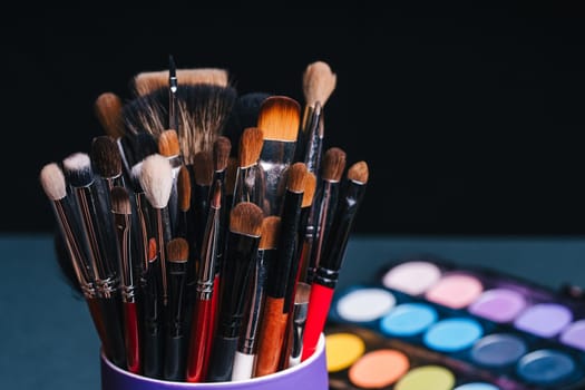 set of makeup brushes on the background of a professional palette with eye shadows close-up. The concept of women's cosmetics for beauty