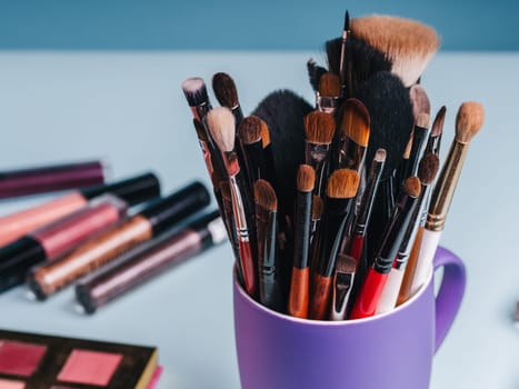 set of professional makeup brushes on the background of a palette with colored eye shadows and other cosmetics for women's beauty