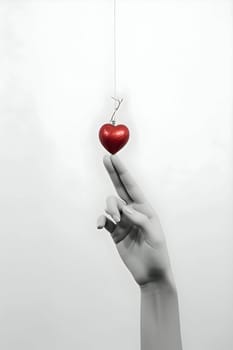 Illustration of fingers delicately pointing towards a red heart-shaped bauble, symbolizing love and affection.
