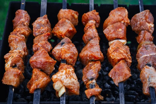 barbecue of pork is prepared on skewers on the grill for a summer picnic