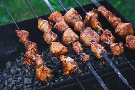 barbecue of pork is prepared on skewers on the grill for a summer picnic