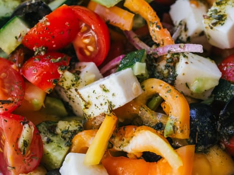 Greek salad with tomatoes, cucumbers, bell peppers, feta cheese and other ingredients close-up