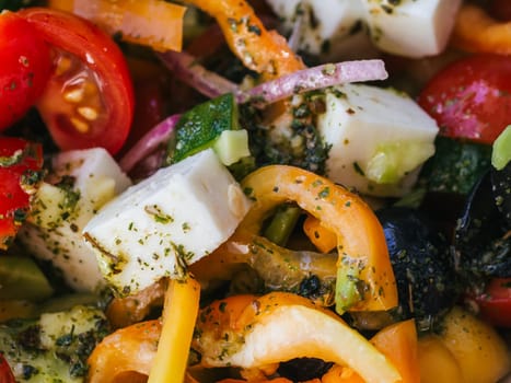 Greek salad with tomatoes, cucumbers, bell peppers, feta cheese and other ingredients close-up