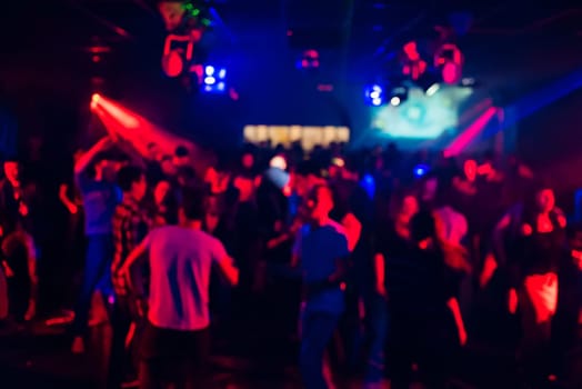 blurred silhouettes of people dancing in a nightclub on the dance floor at a party
