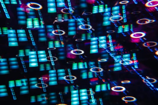 DJ mixer in a nightclub with a background of glowing lights from buttons and controllers