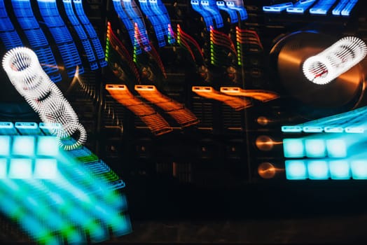 DJ mixer in a nightclub with glowing colored lights from controllers and buttons in the nightclub