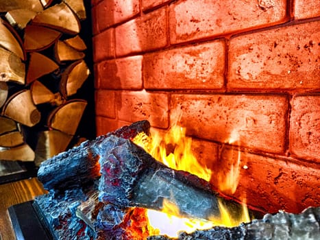 Fireplace. Firebrands, fire and a brick wall on the background. Firebrands ablaze with a cozy flame against a brick backdrop