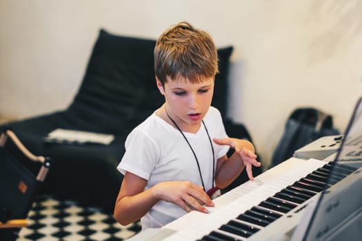 Young boy Portrait sitting at digital piano Playing keyboard focused kid activity indoors press on Key learning to play music room Hobby.