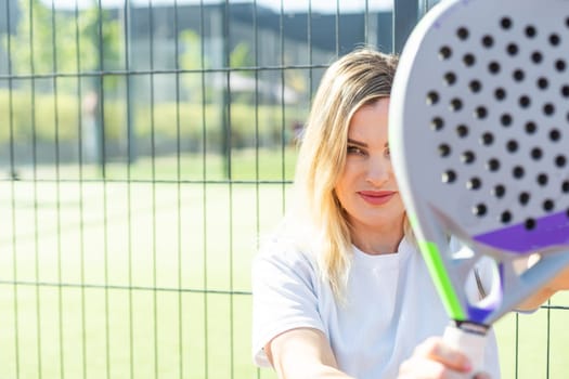 Happy female paddle tennis player during practice on outdoor court looking at camera. Copy space. High quality photo