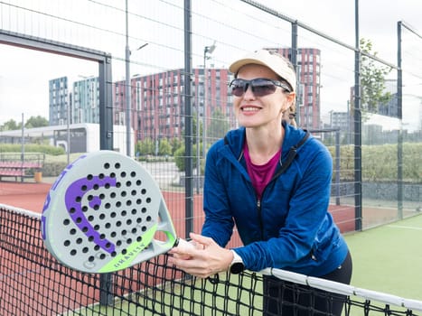 Ukraine Kyiv, May 10 2024. Portrait of smiling woman with padel tennis racket head at court. High quality photo