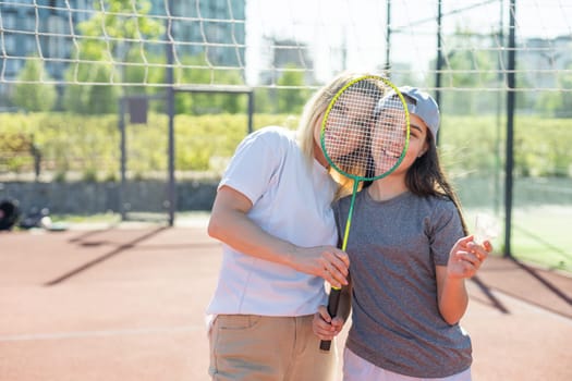 Mother and daughter are playing badminton outside in the yard on summer hot day. High quality photo