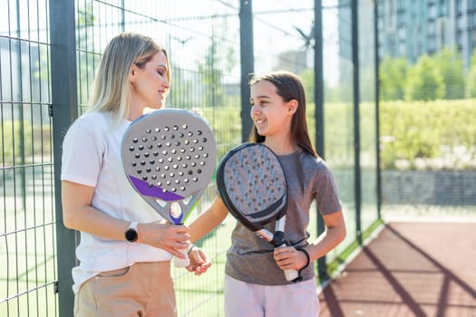 Beautiful girls getting ready for a workout on the padel tennis court. High quality photo