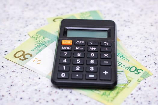 A portable communications device with a numeric keypad, also known as a calculator, is placed on a stack of money, serving as office equipment and a useful gadget