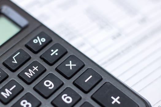 A closeup of a calculator, a peripheral input device, on top of a sheet of paper, office equipment often used with a computer keyboard or personal computer for calculations