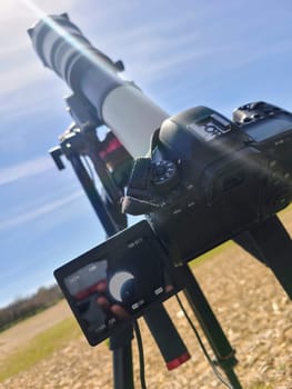 Professional DSLR with telephoto lens on tripod, showing the sun and moon beginning to overlap for the upcoming Total Eclipse of 2024.