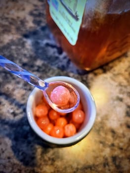 Spoon lifting peach pink boba with honey from bowl.