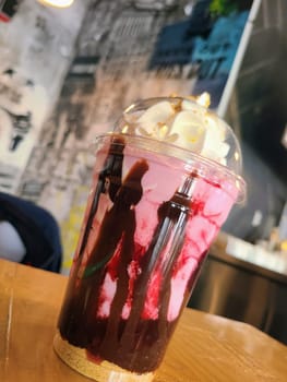 Colorful layered milkshake in trendy Fort Wayne cafe, with urban-themed mural backdrop.