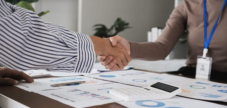 Two Asian businesswomen shaking hands in the office. Concept of partnership and agreement.